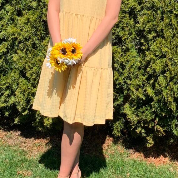 Sleeveless golden yellow trapeze knee-length dress with high halter neckline, and sunflower accent.
