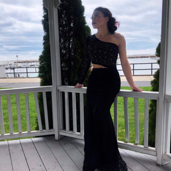 Black one sleeve floor-length gown with sequins on the bust, sleeve, and train of the gown with a cutout design on the waist.