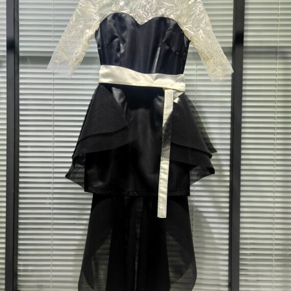 This 2 piece look begins with a black sweetheart neckline mini shift with contrasting white inset lace bodice, mandarin collar and elbow length sleeves. This mini is styled with a high low peplum two layer black tulle skirt tied at the waist with white satin bow.