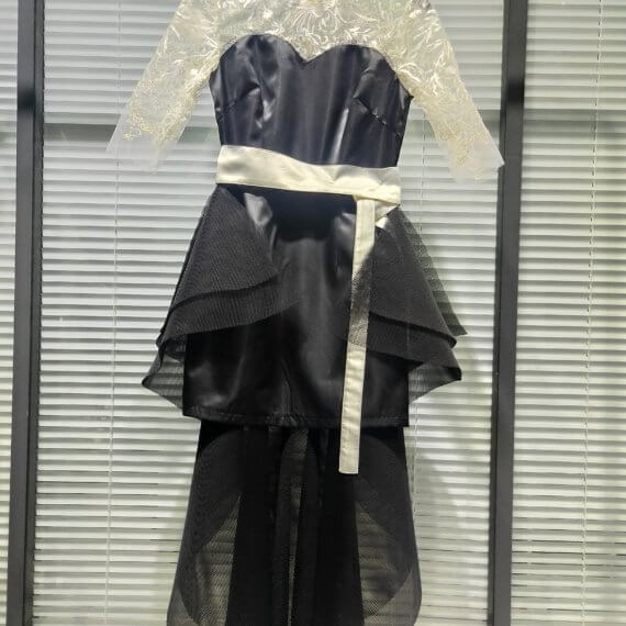 This 2 piece look begins with a black sweetheart neckline mini shift with contrasting white inset lace bodice, mandarin collar and elbow length sleeves. This mini is styled with a high low peplum two layer black tulle skirt tied at the waist with white satin bow.