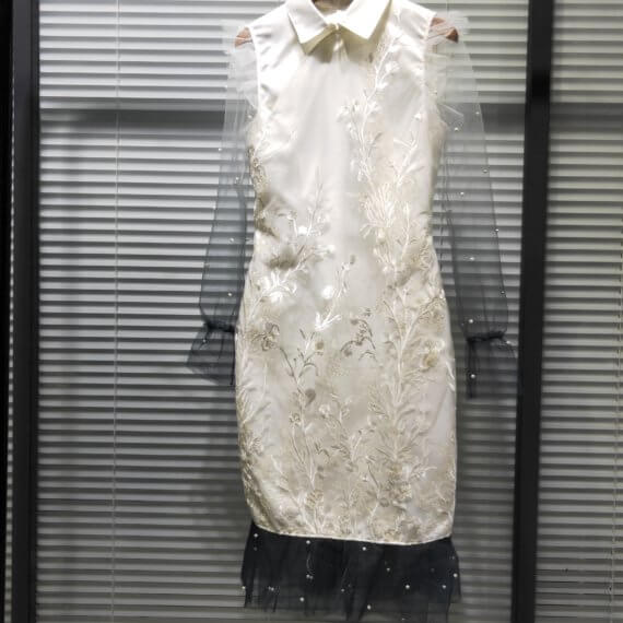 White silk satin shift dress with white floral embroidered overlay and a windsor collar. This dress has ombre white to black shear, chiffon long sleeves and finishes with 2 layers of black, pearl beaded chiffon ruffles at the hem.