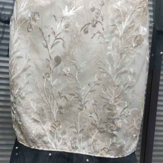 White silk satin shift dress with white floral embroidered overlay and a windsor collar. This dress has ombre white to black shear, chiffon long sleeves and finishes with 2 layers of black, pearl beaded chiffon ruffles at the hem.