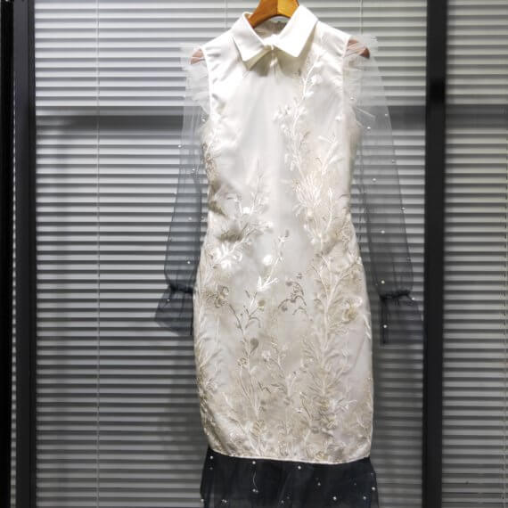 White silk satin shift dress with white floral embroidered overlay and a windsor collar. This dress has ombre white to black shear, chiffon long sleeves and finishes with 2 layers of black, pearl beaded chiffon ruffles at the hem.