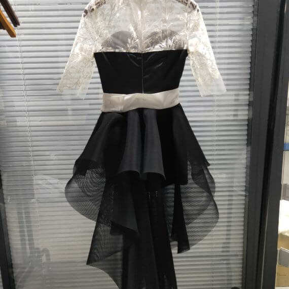 This 2 piece look begins with a black sweetheart neckline mini shift with contrasting white inset lace bodice, mandarin collar and elbow length sleeves. This mini is styled with a high low peplum two layer black tulle skirt tied at the waist with white satin bow.