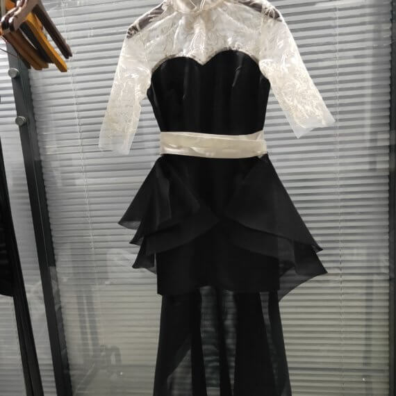 This 2 piece look begins with a black sweetheart neckline mini shift with contrasting white inset lace bodice, mandarin collar and elbow length sleeves. This mini is styled with a high low peplum two layer black tulle skirt tied at the waist with white satin bow.
