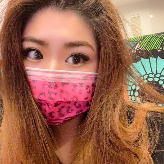 A girl wearing a hot pink cheetah print mask with white stripes going across the nose